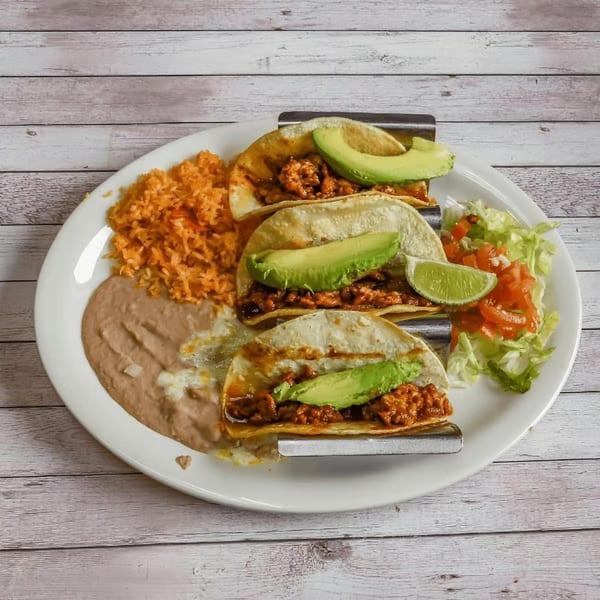 Three tacos with meat and avocado, served with rice, refried beans, and a side salad.